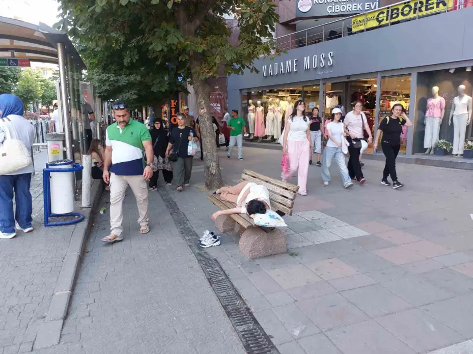 Sıcaktan bunalan genç gölgelik bankta yastıkla beraber uyudu